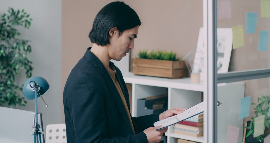 Middle-aged professional man reading a printed document at his desk